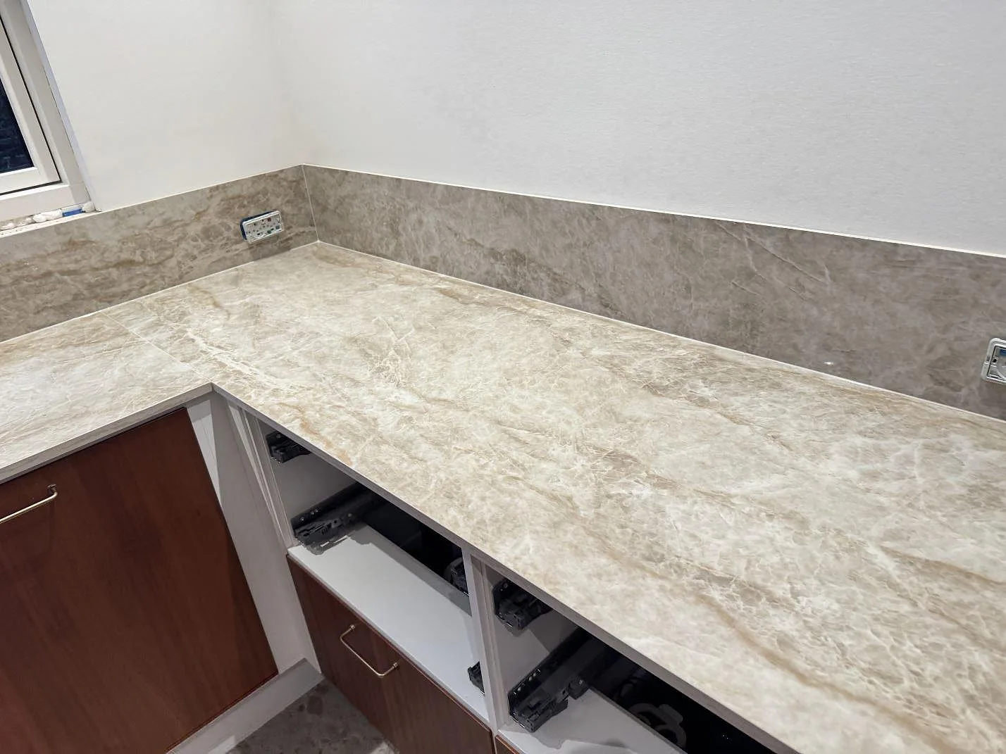 Köksbänkskiva i polerad Dekton Taga keramik med låg stänkkant längs ett L-format kök i Glostrup.