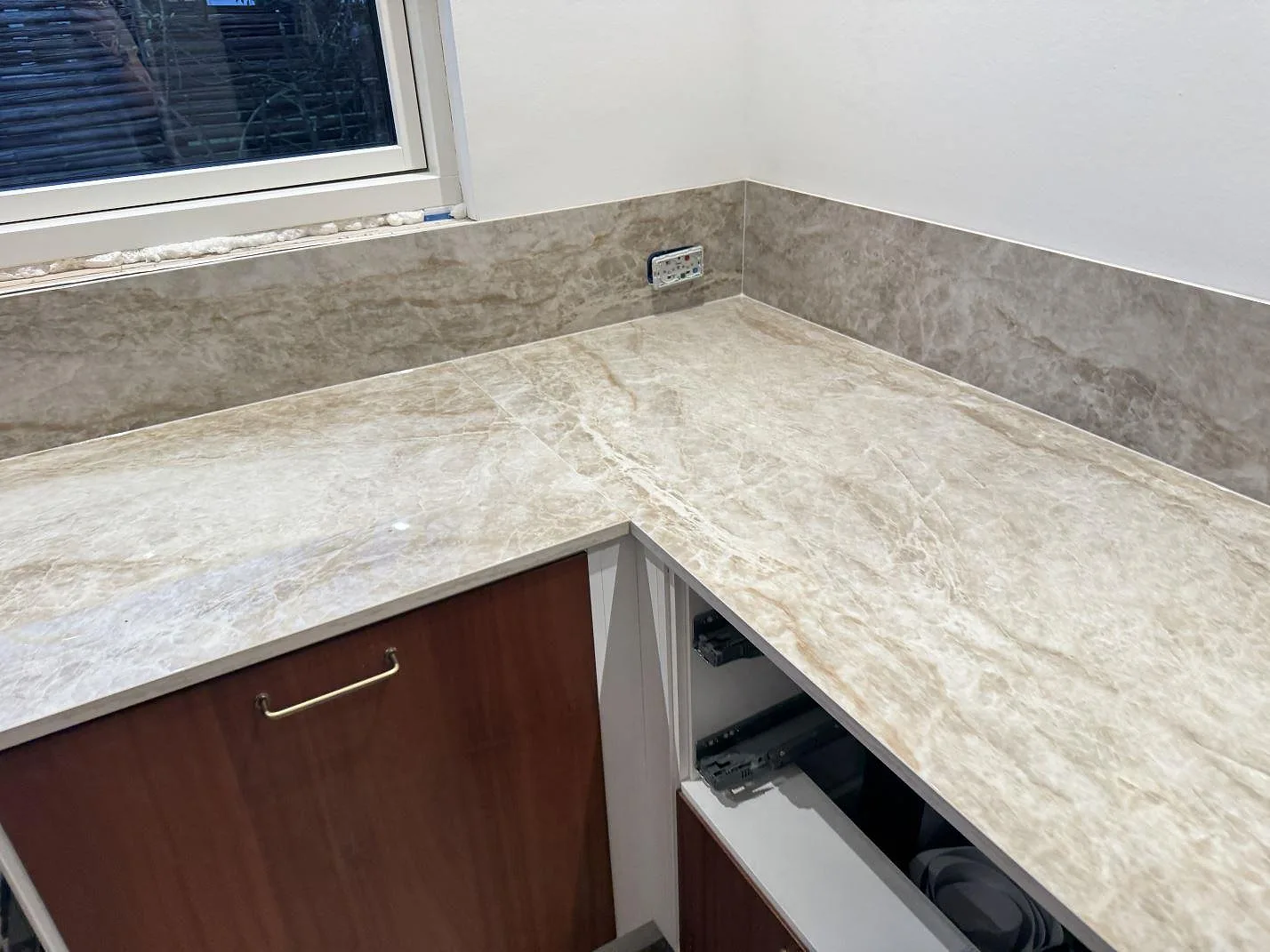 Polerad köksbänkskiva i Dekton Taga under fönster med matchande stänkskydd i ett kök i Glostrup.