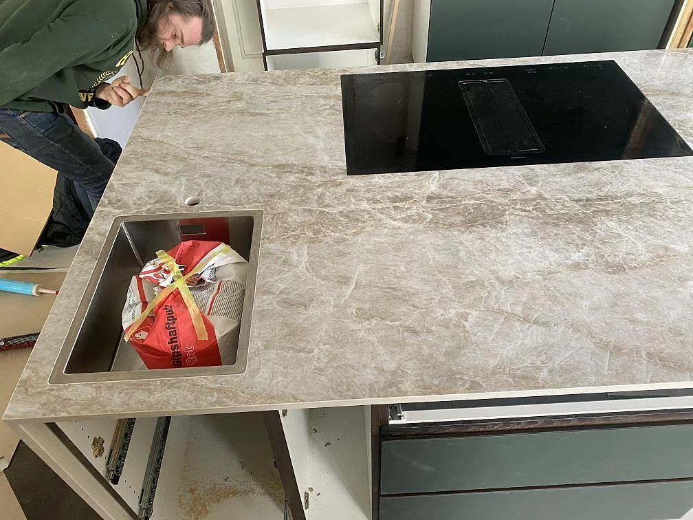 Köksbänkskiva i Dekton Taga med underlimmad rostfri diskho och infälld induktionshäll på köksön i ett kök i Göteborg.