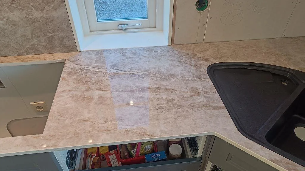 Polerad Dekton Taga köksbänkskiva i Grästorp med svart underlimmad kompositdiskho i hörnet och blank reflekterande yta.