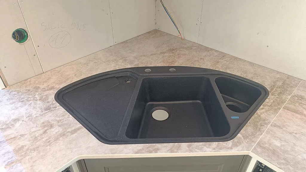 Stor svart kompositdiskho placerad på Dekton Taga köksbänkskiva i Grästorp inför infällning under montering.