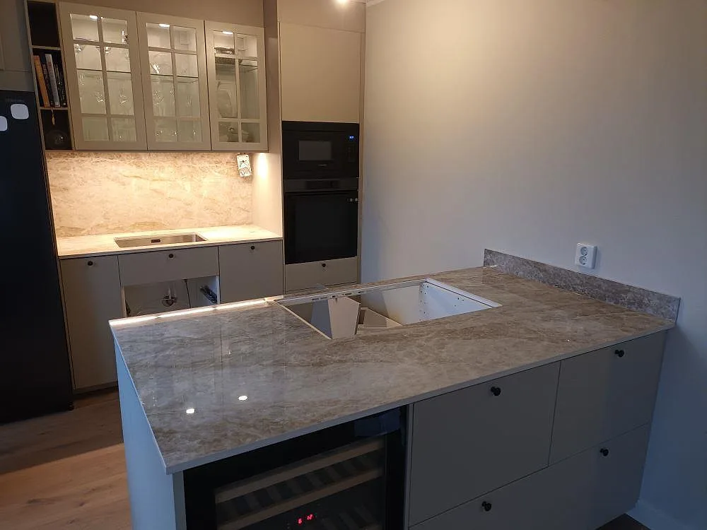 Köksö i Dekton Taga med förberedd håltagning för häll och vinkyl under, polerad keramikbänkskiva i ett kök i Hägersten under montering.