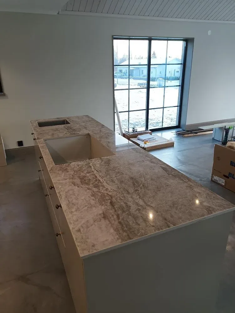 Närbild av polerad Dekton Taga på köksö med tydlig ådring och urtag under montering i Hedemora.