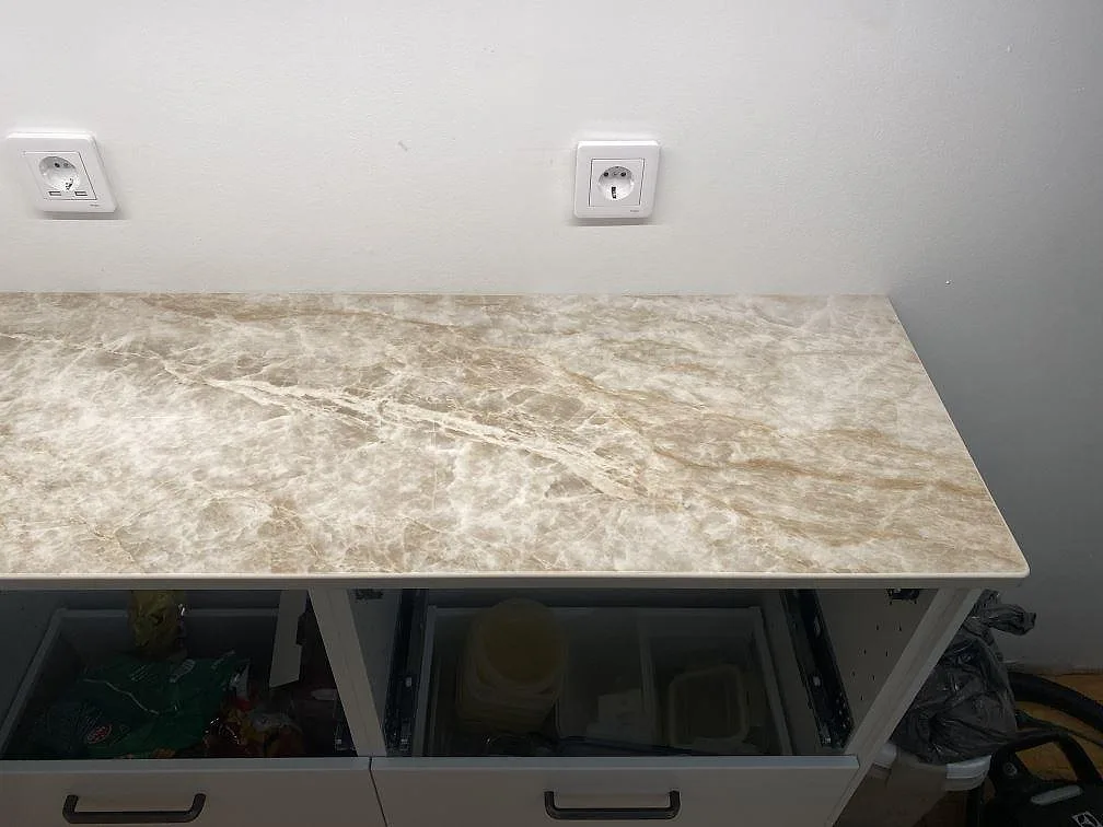 Installerad Dekton Taga bänkskiva i polerad finish med ljus ådring ovanför vita köksstommar i Hindås.