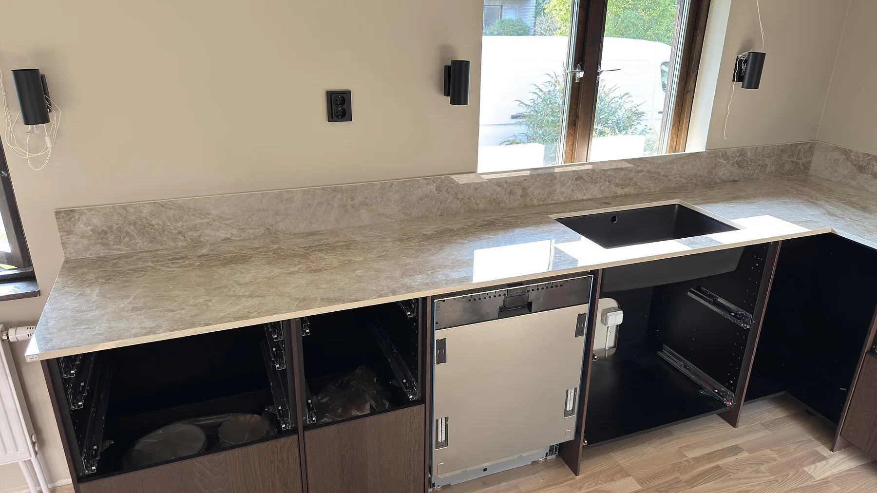 Närbild av polerad Dekton Taga köksbänkskiva med svart diskho, stänkskydd och grå ådring i Järfälla.