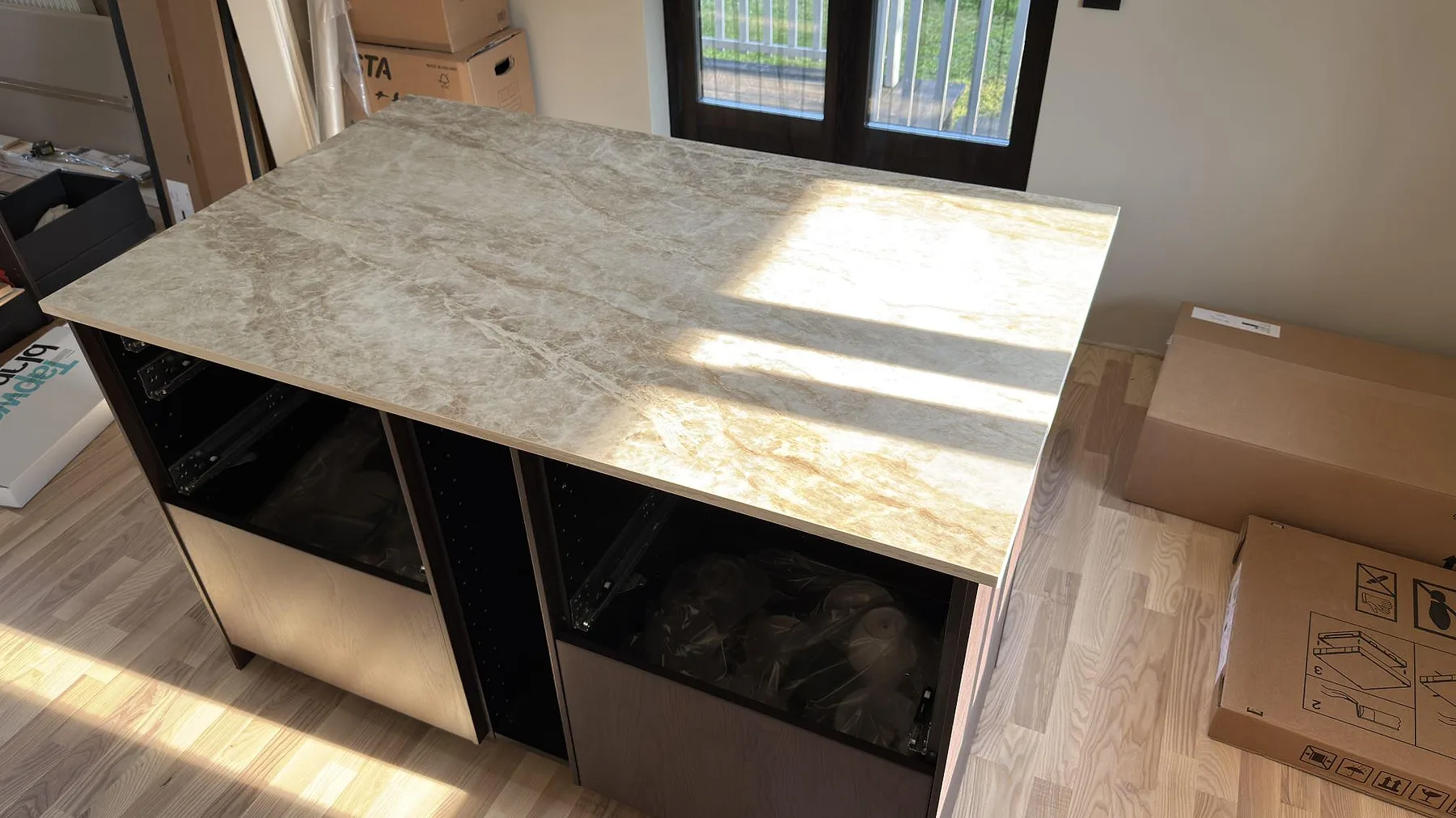 Köksö med polerad Dekton Taga bänkskiva i keramik, ljus grå ådring och monteringsmiljö i Järfälla.
