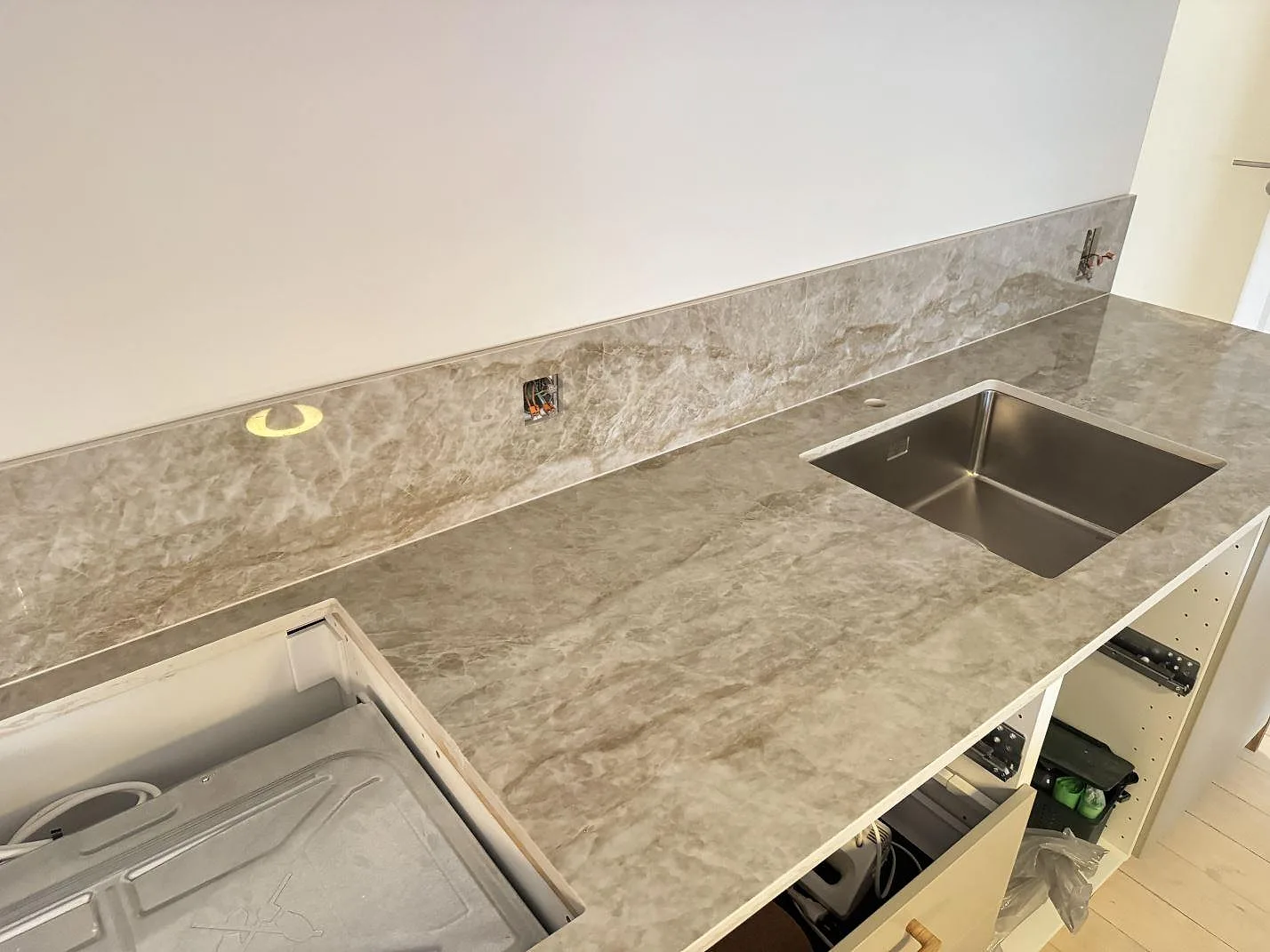 Polerad köksbänkskiva i Dekton Taga, keramik, med lång stänkkant, diskho och hällurtag under montering i Köpenhamn V.