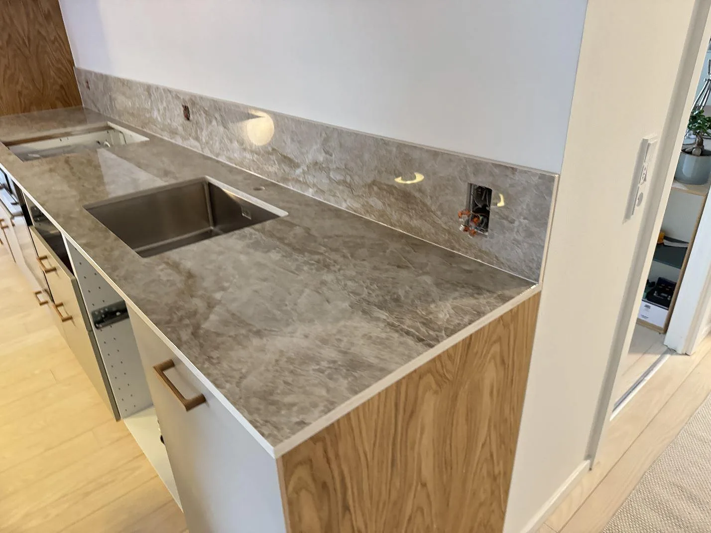 Sidovy av polerad Dekton Taga, keramik, som köksbänkskiva med stänkskydd och rostfri diskho i Köpenhamn V.