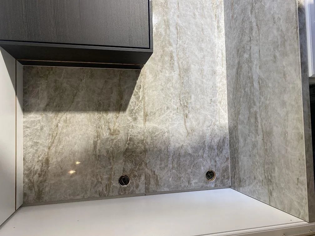 Stänkskydd i polerad Dekton Taga med urtag för eluttag bakom köksbänkskivan i ett kök i Kristianstad.