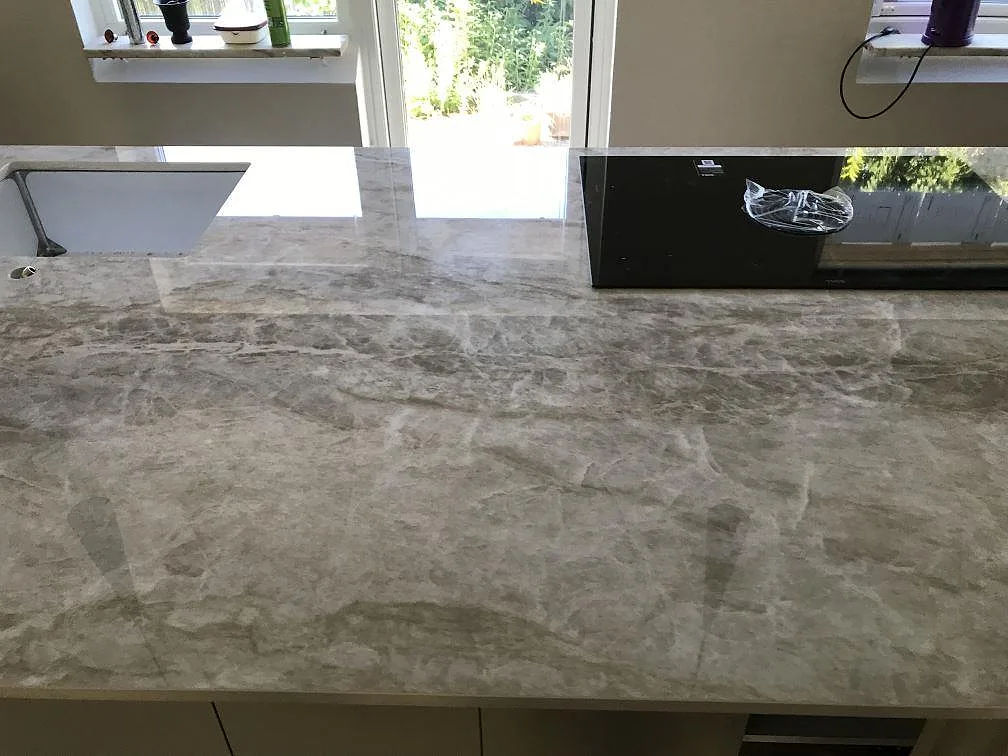 Polerad Dekton Taga köksbänkskiva med underlimmad diskho och infälld häll vid fönstret i ett kök i Limhamn.