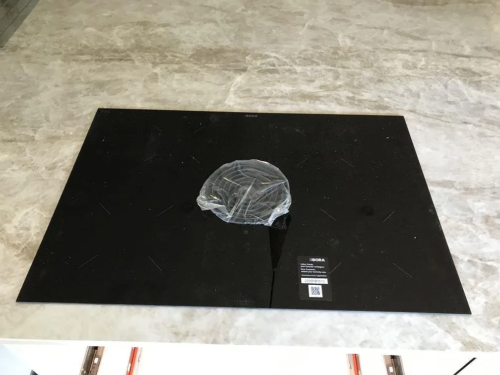 Infälld BORA induktionshäll i en polerad Dekton Taga köksbänkskiva, sedd ovanifrån i ett kök i Limhamn.