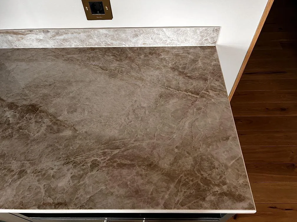 Närbild av polerad Dekton Taga keramik som köksbänkskiva med låg stänkkant i ett kök i Limhamn.