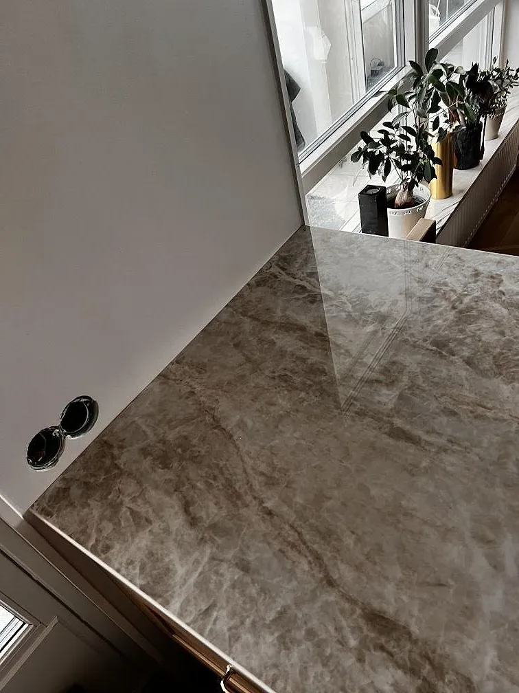 Polerad Dekton Taga keramik på köksö med spegling från fönster och markerad marmorlik ådring i Limhamn.