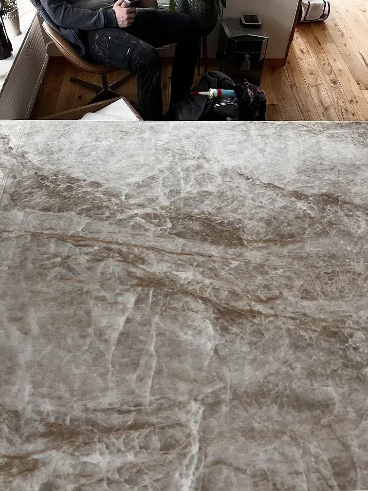 Ytnära bild av polerad Dekton Taga keramik med gråbeige ådring under montering i köket i Limhamn.