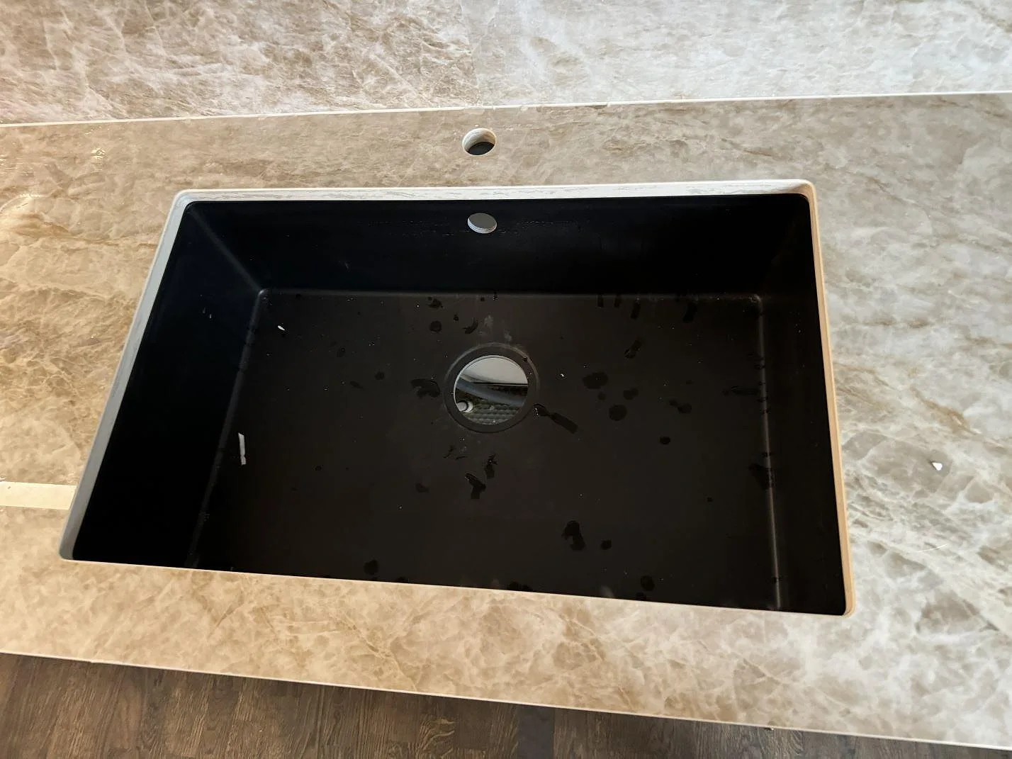 Närbild på svart diskho i polerad Dekton Taga med gråbeige ådring och stänkskydd i Malmö.