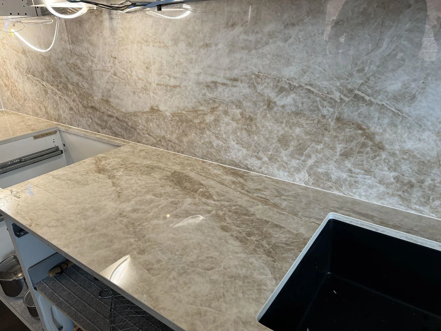 Vinkelvy av polerad Dekton Taga som köksbänkskiva med svart diskho och hög väggbeklädnad i Malmö.