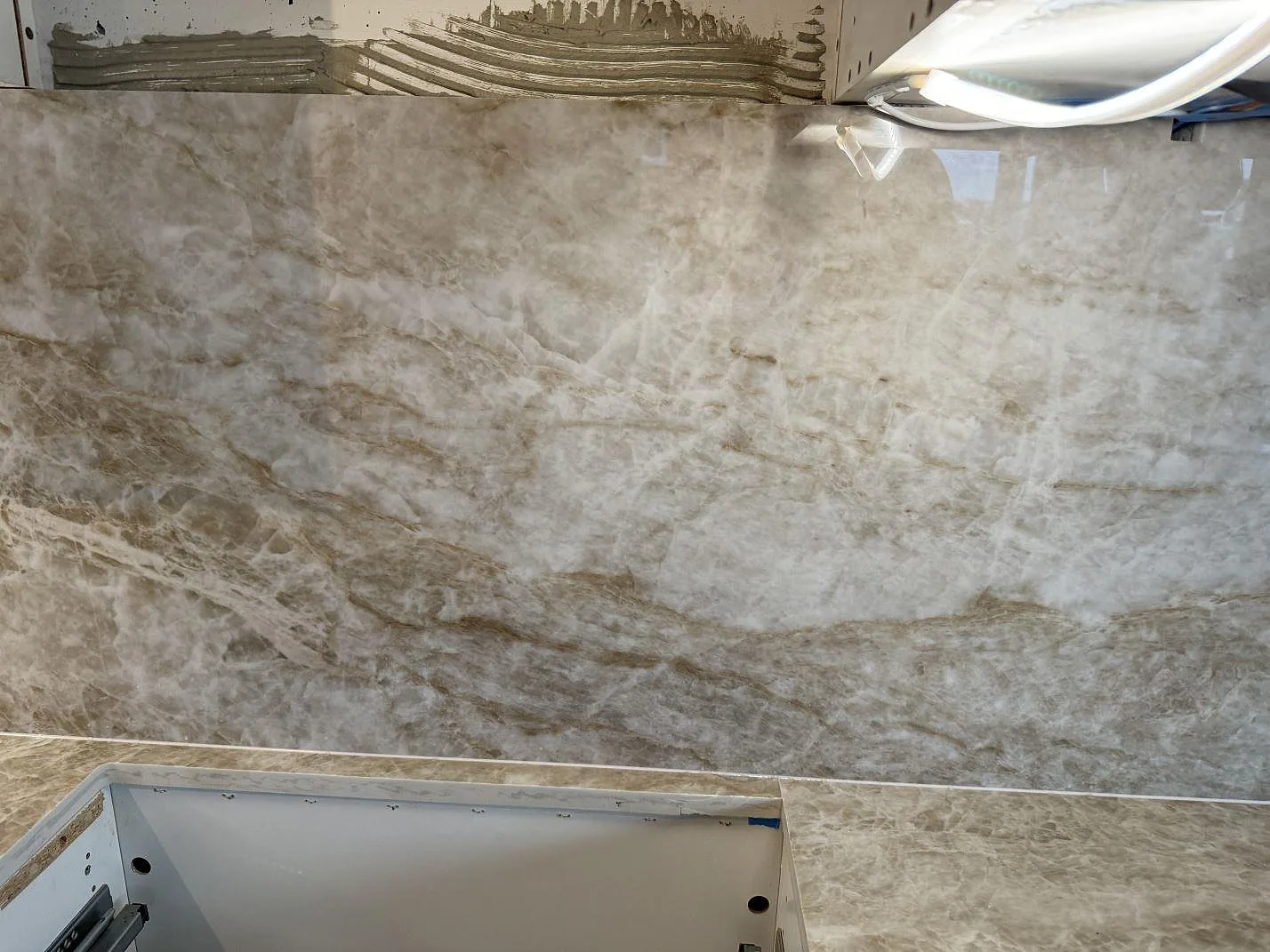 Detalj av polerad Dekton Taga på arbetsyta och väggbeklädnad under montering i ett kök i Malmö.