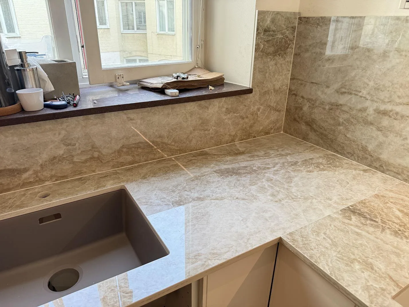 Köksbänkskiva i polerad Dekton Taga keramik med grå diskho och matchande stänkskydd i ett kök i Malmö.