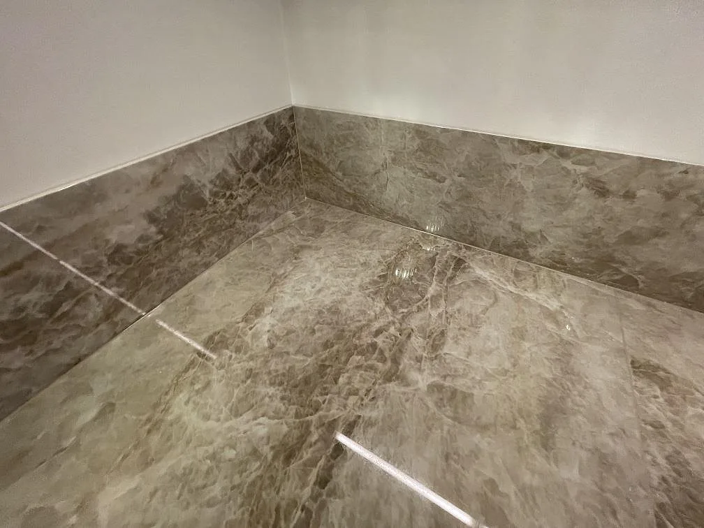 Detalj av fönsterbänk och väggbeklädnad i polerad Dekton Taga, varmgrå keramik med mjuk ådring, i ett kök i Stockholm.