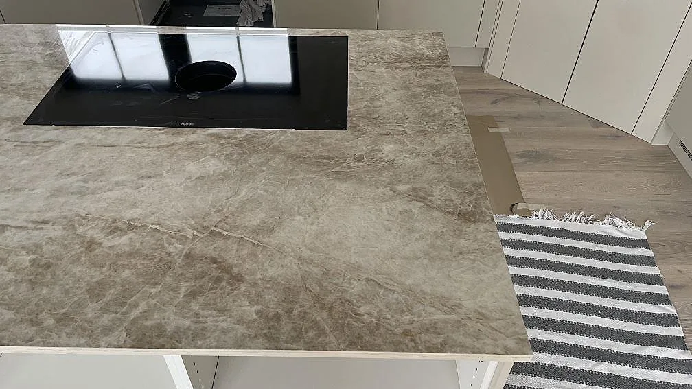 Polerad Dekton Taga bänkskiva med svart häll, ljus marmorering och rak framkant i Trelleborg.
