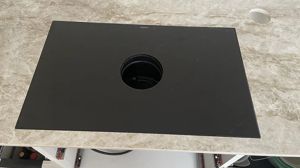 Detalj av svart häll på gråbeige Dekton Taga keramik med polerad yta i ett kök i Trelleborg.