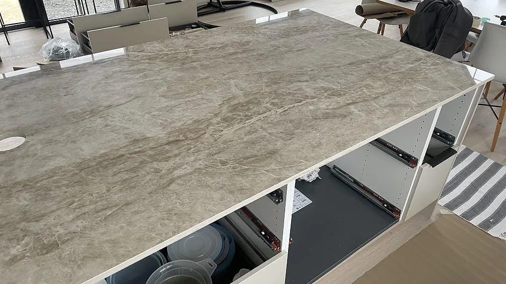 Stor köksö med polerad Dekton Taga bänkskiva och gråbeige marmorering i ett kök i Trelleborg.