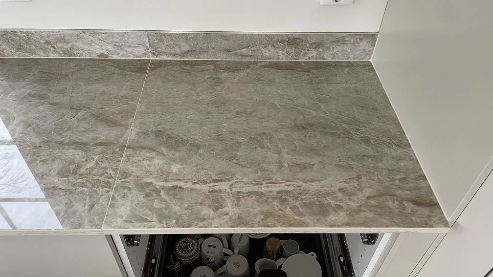 Sidobänk i polerad Dekton Taga med matchande stänkskydd och marmorerad keramikyta i Trelleborg.