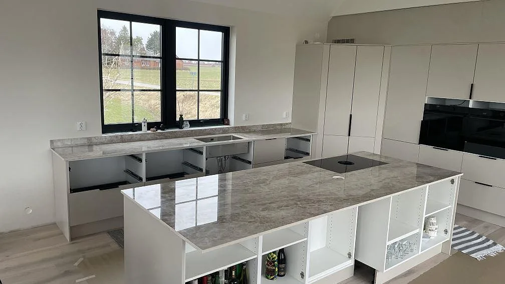 Köksbänkskiva i gråbeige Dekton Taga, polerad keramik, med stor köksö och väggbänkar i Trelleborg.