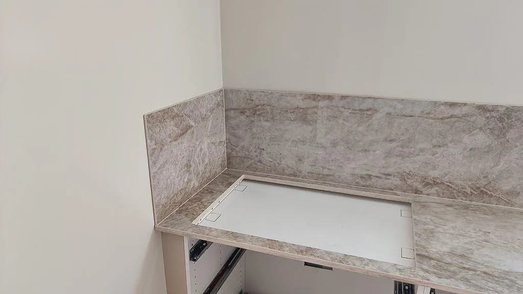 Hörn av köksbänkskiva i polerad Dekton Taga med stänkskydd och arbetsyta i köket i Trollhättan.