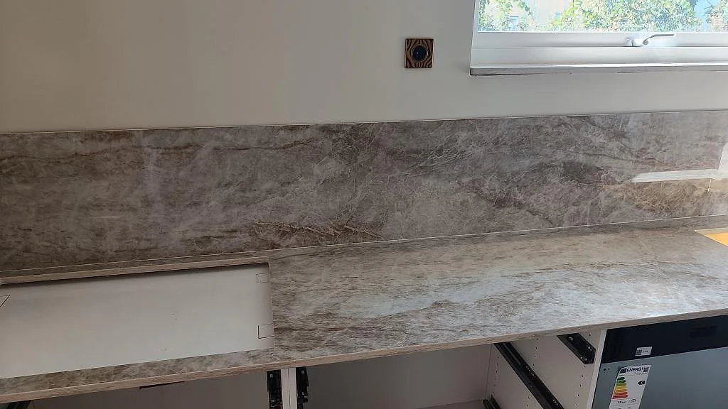 Väggbänk i polerad Dekton Taga, keramik, med matchande stänkskydd under fönster i Trollhättan.