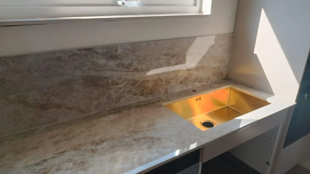 Närbild av polerad Dekton Taga vid diskho och fönster, med gråbeige ådring i köket i Trollhättan.