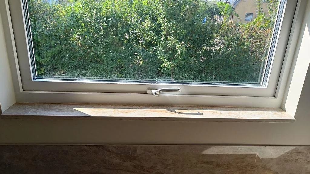 Fönsternisch med polerad Dekton Taga, keramik, där stänkskydd och fönsterkant möts i Trollhättan.