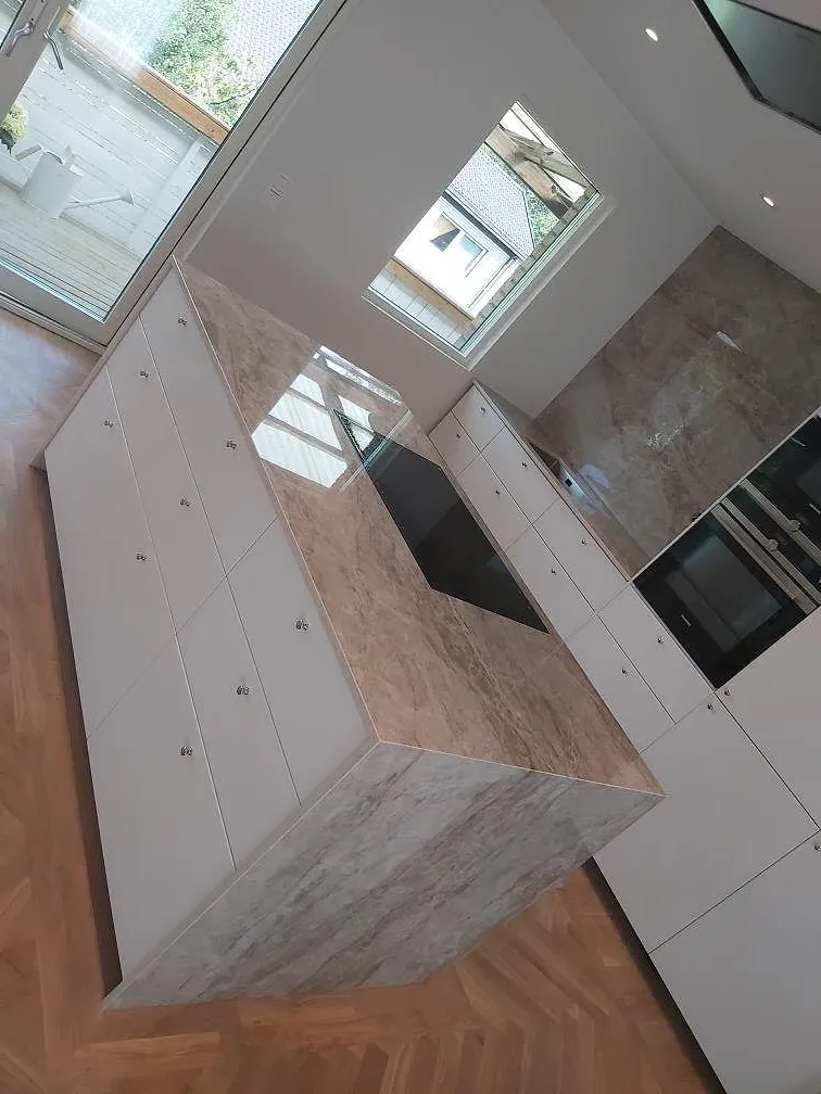 Närbild av köksö i polerad Dekton Taga med svart häll och ådrad keramik runt sidorna i TYresö.