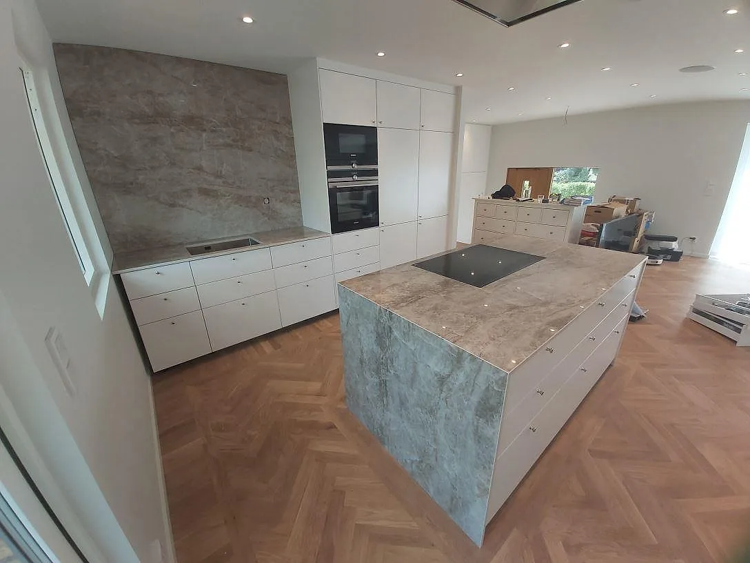 Köksbänkskiva i Dekton Taga, polerad keramik, med stor köksö, svart häll och matchande väggbeklädnad i TYresö.