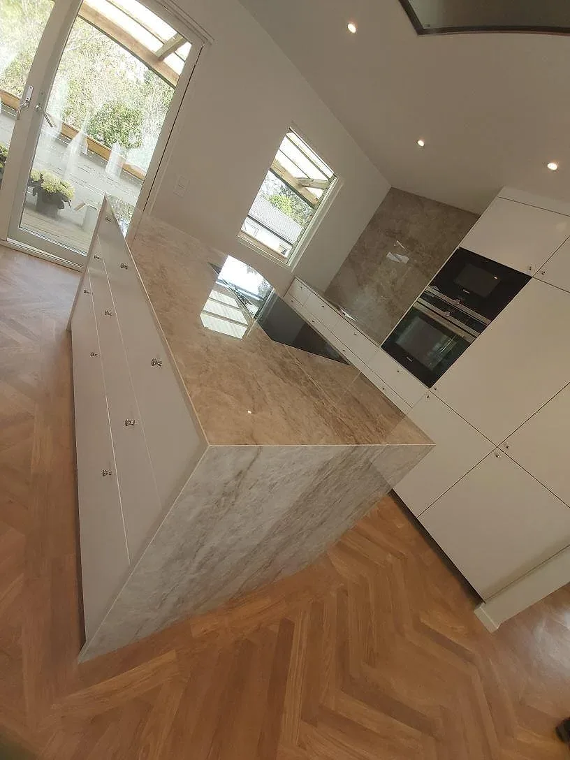 Monterad köksö i Dekton Taga, polerad keramik, med vattenfallskant och ljusa köksskåp i TYresö.