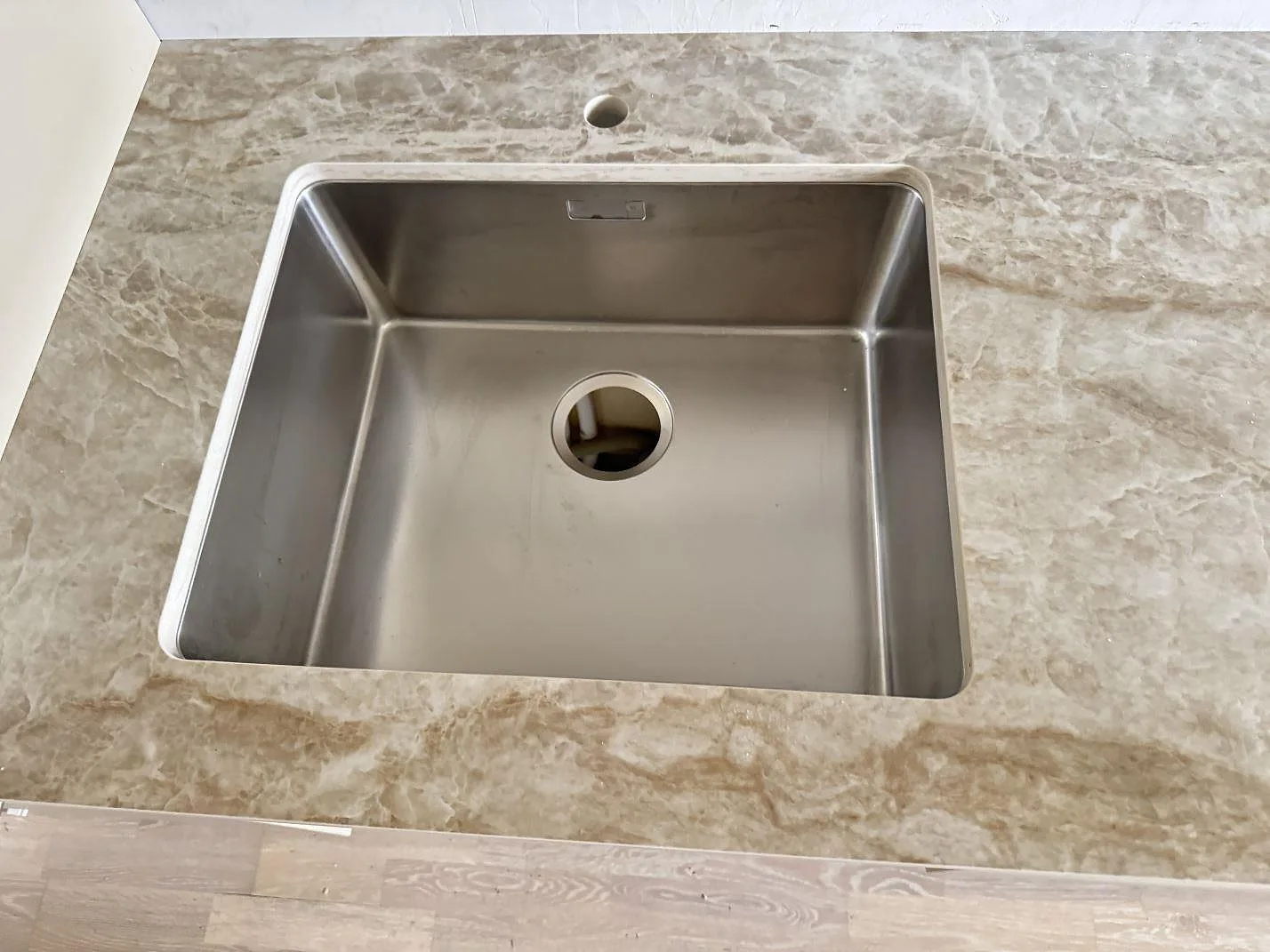 Närbild på rostfri diskho i polerad Dekton Taga köksbänkskiva med gråbeige ådring i Västra Frölunda.