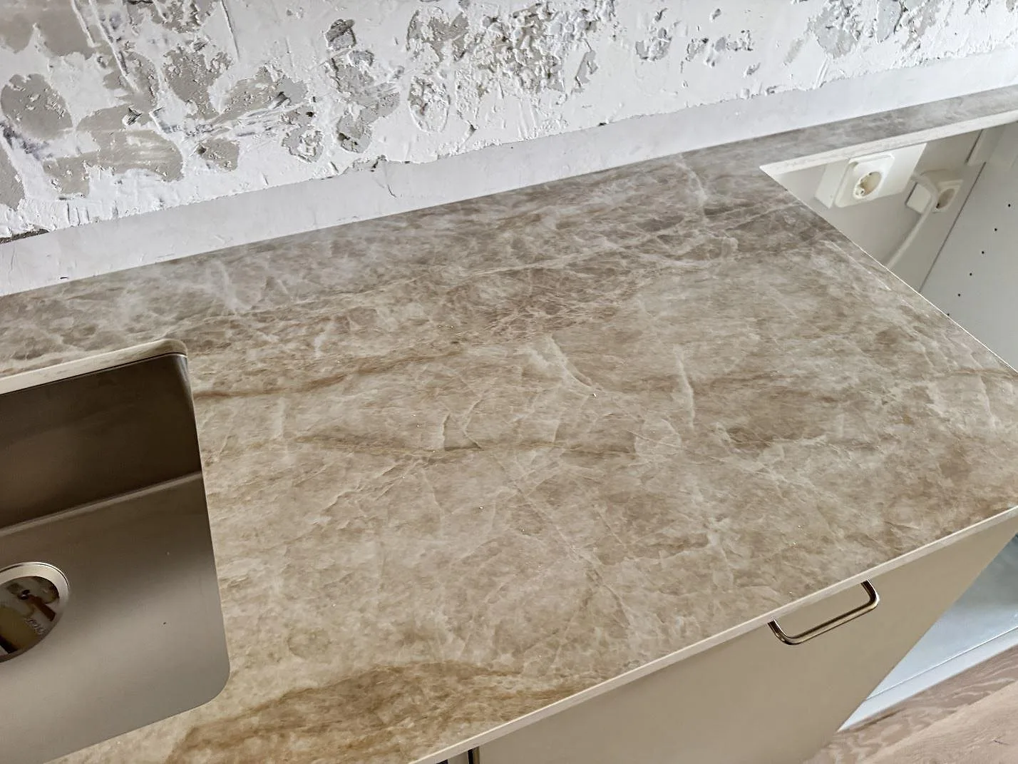 Arbetsyta i polerad Dekton Taga keramik bredvid diskhon, med ljus ådring och vägg under arbete i Västra Frölunda.