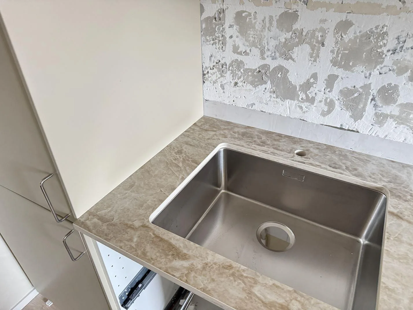 Polerad köksbänkskiva i Dekton Taga keramik med rostfri diskho och rå väggyta under montering i Västra Frölunda.