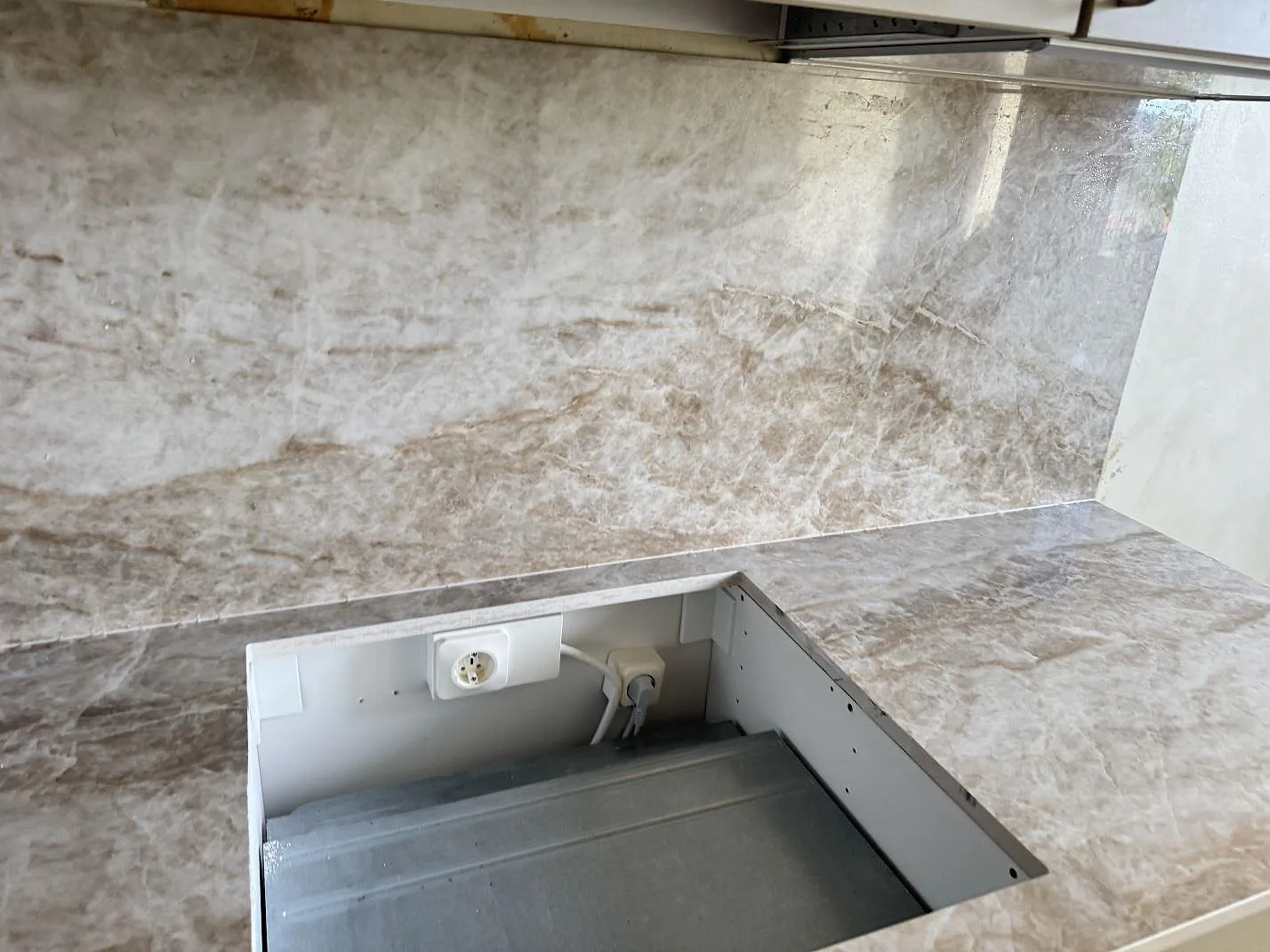 Närbild av hällurtag i en polerad Dekton Taga köksbänk med matchande keramik bakom arbetsytan i Västra Frölunda.