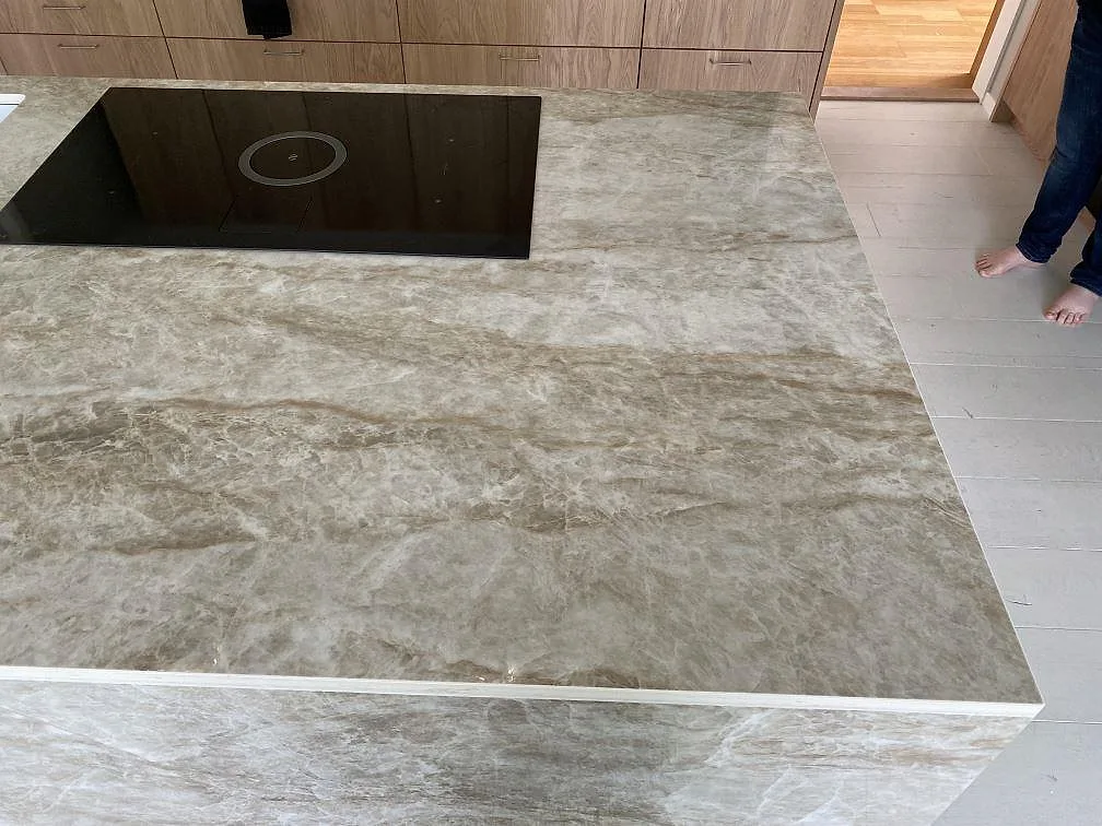 Sida på köksö i polerad Dekton Taga med markant ådring och tejpad montering i ett kök i Växjö.