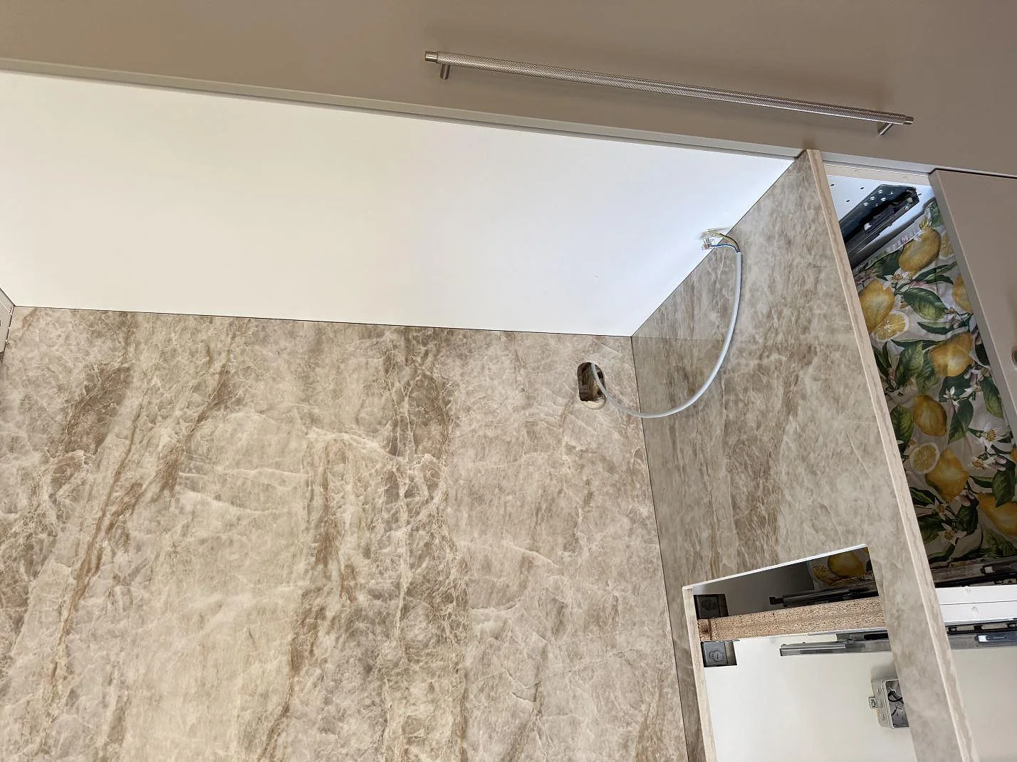 Väggskivor och bänkskiva i polerad Dekton Taga keramik med ljus gråbeige ådring runt köksnischen i Virum.