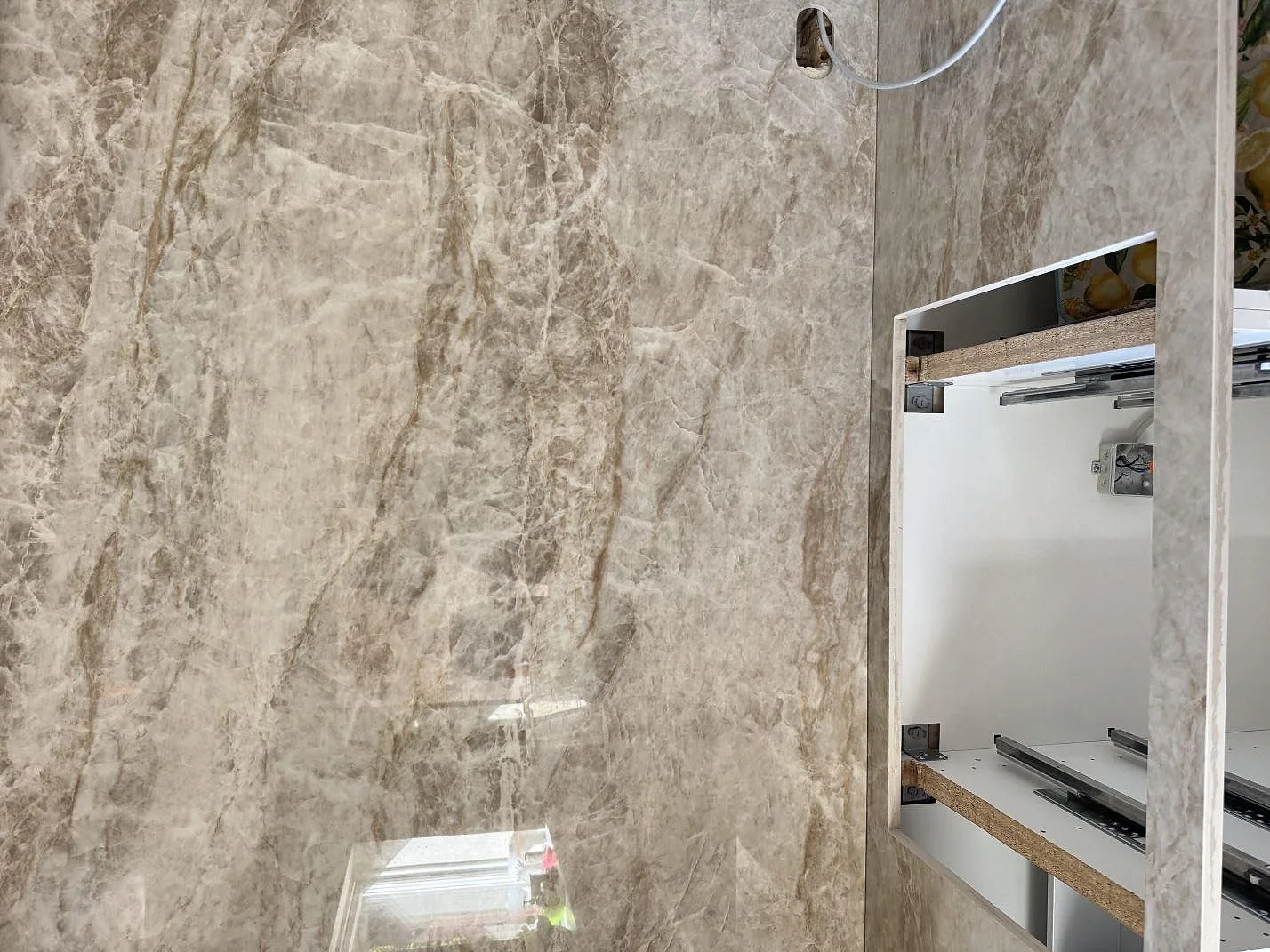 Detalj av polerad Dekton Taga väggbeklädnad med blank yta, ljus ådring och öppen köksstomme i Virum.