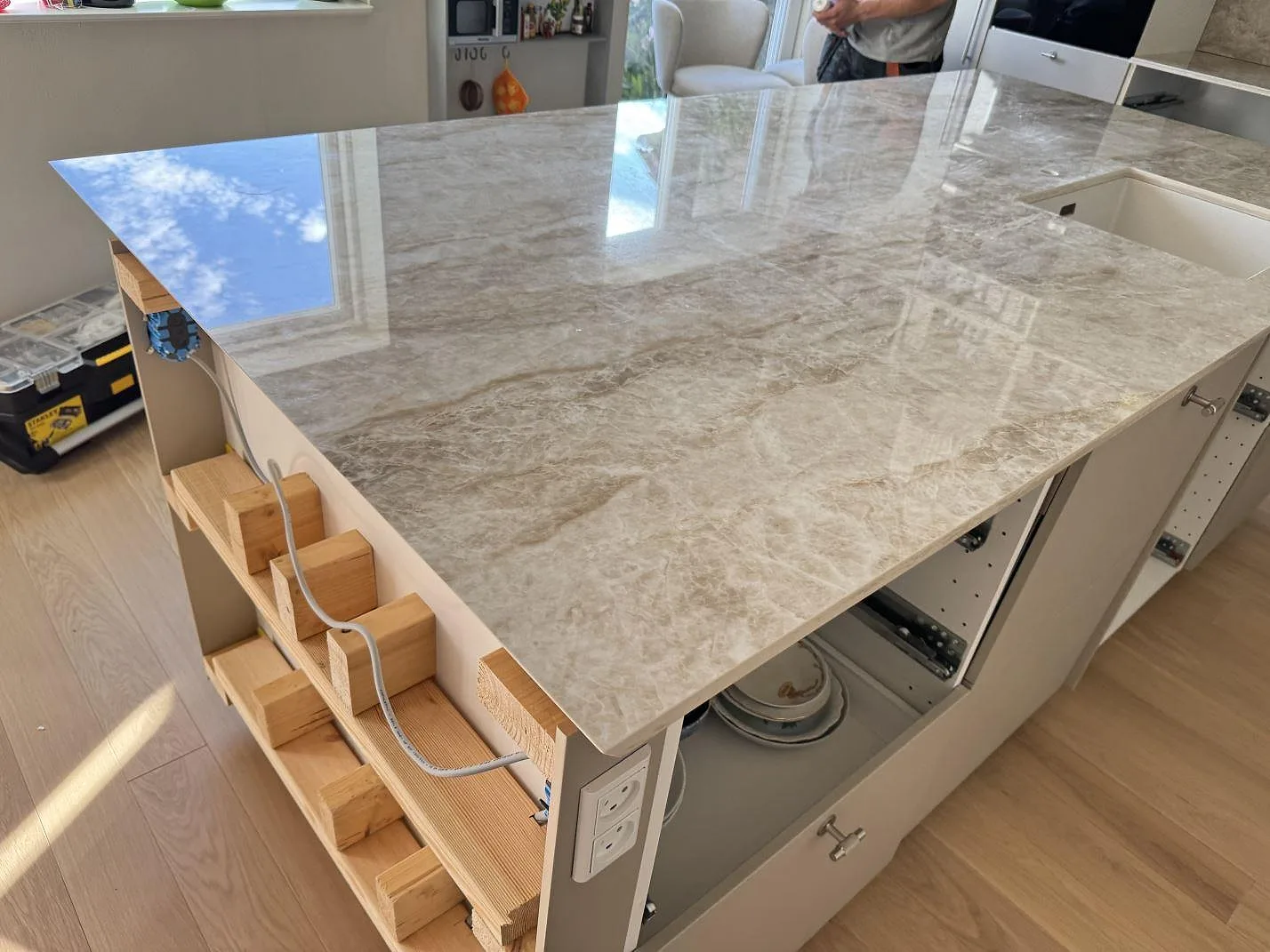 Blank arbetsö i polerad Dekton Taga keramik med speglingar i ytan, vit diskho och kök under montering i Virum.