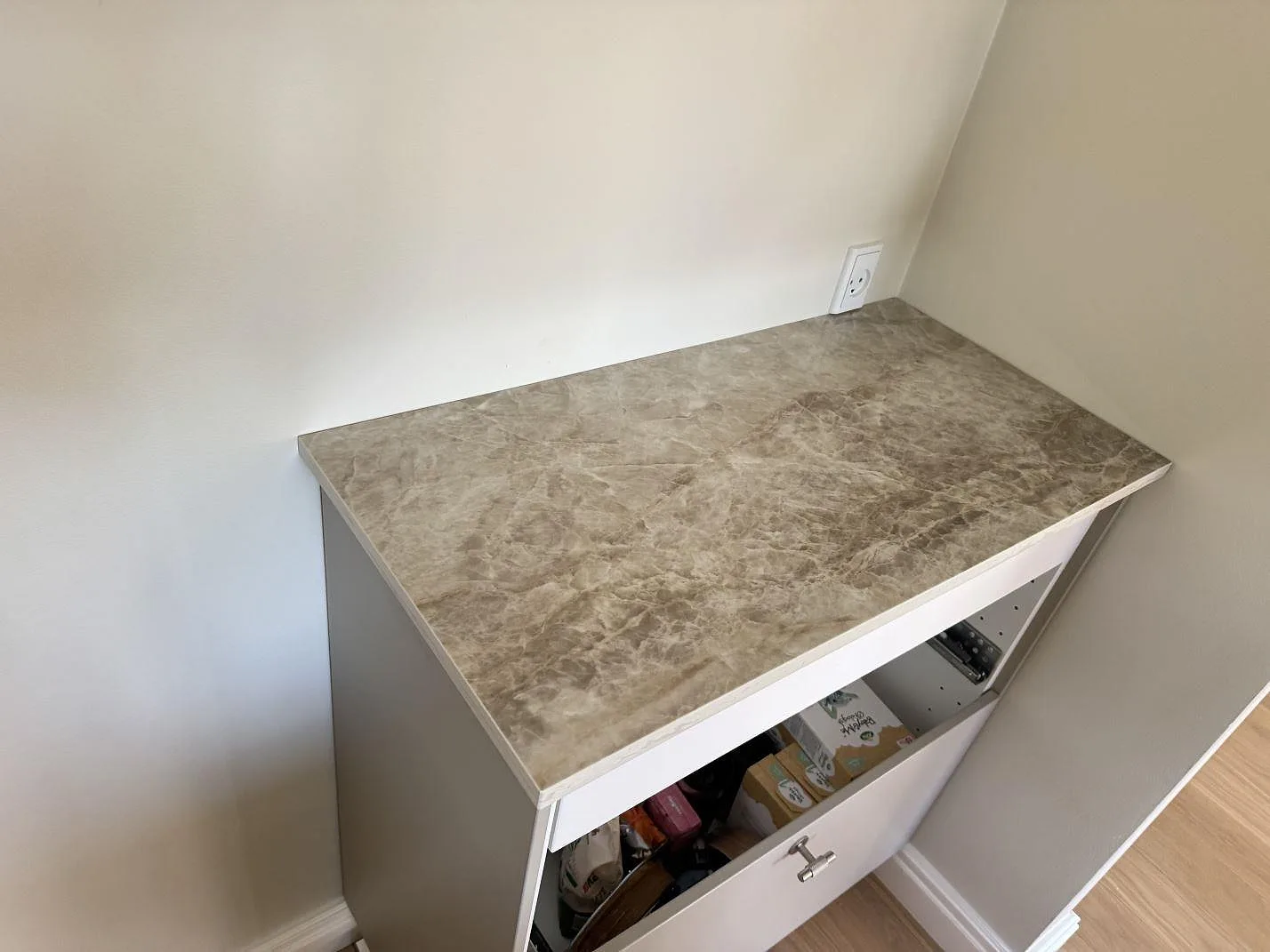 Installerad toppskiva i polerad Dekton Taga keramik på en låg förvaringsmöbel med vägguttag i Virum.