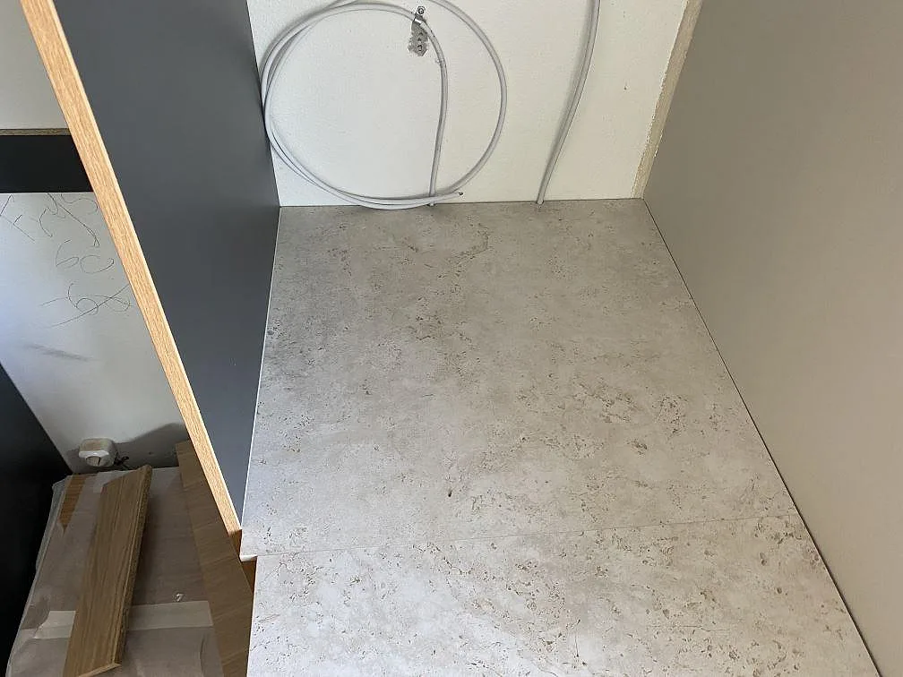 Detalj av matt Dekton Tk05 Sabbia som bänkskiva i nisch bredvid högskåp under montering i Birkerød.