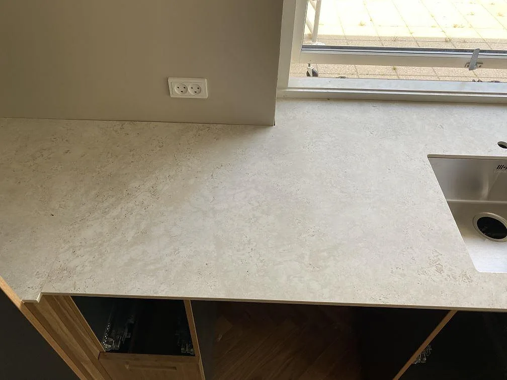Matt Dekton Tk05 Sabbia som köksbänkskiva vid fönster med rostfri diskho och ljus stenstruktur i Birkerød.