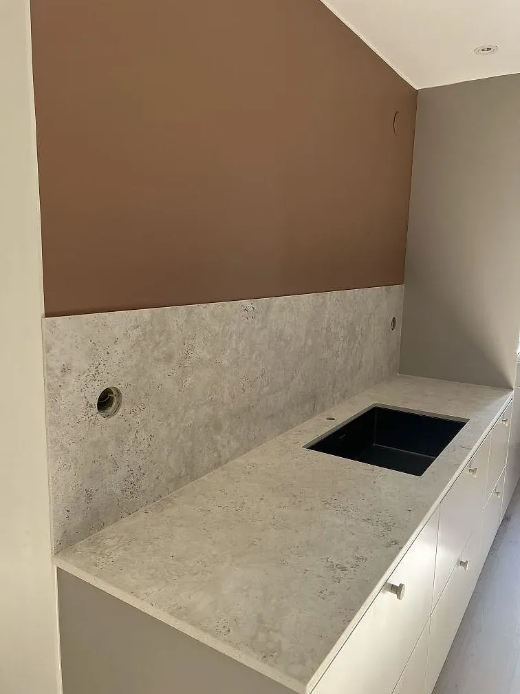 Badrumsbänkskiva i matt Dekton Tk05 Sabbia med svart tvättställ och matchande väggbeklädnad i Bunkeflostrand.