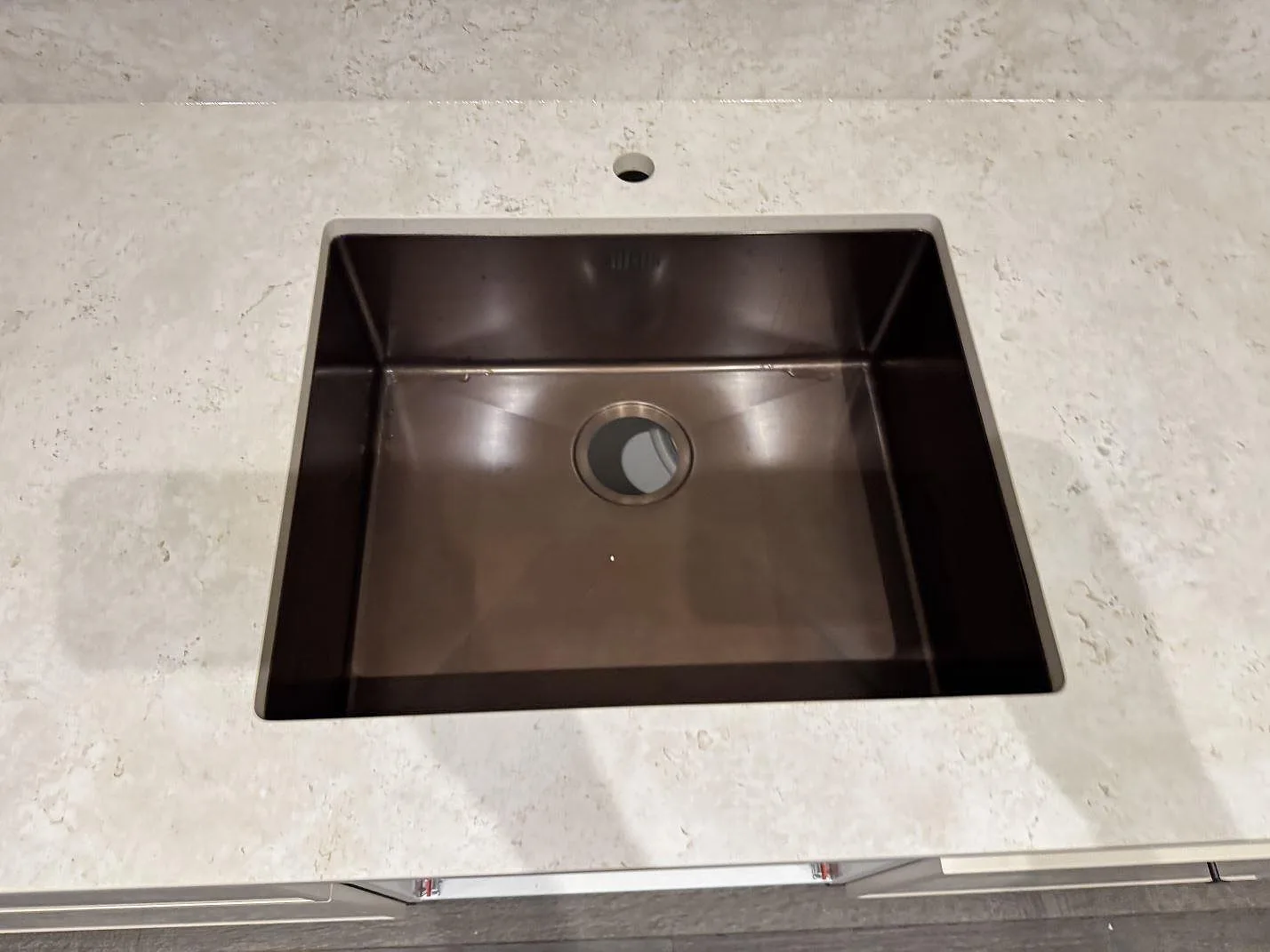 Närbild på mörk diskho i matt keramisk köksbänkskiva av Dekton Tk05 Sabbia med ljus ådring i Copenhagen.
