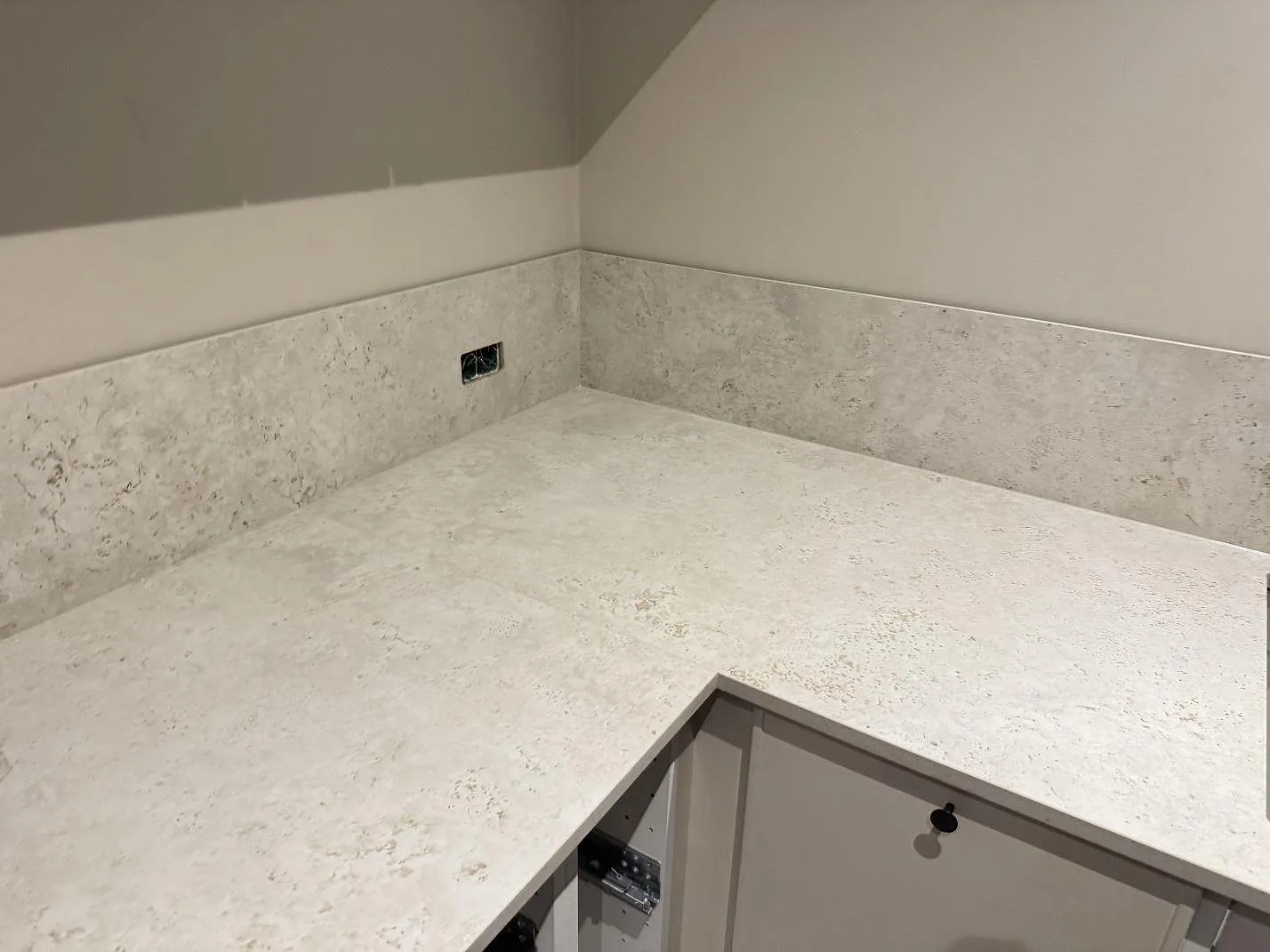 Hörnparti i kök med matt keramisk bänkskiva i Dekton Tk05 Sabbia och lågt stänkskydd i Copenhagen.