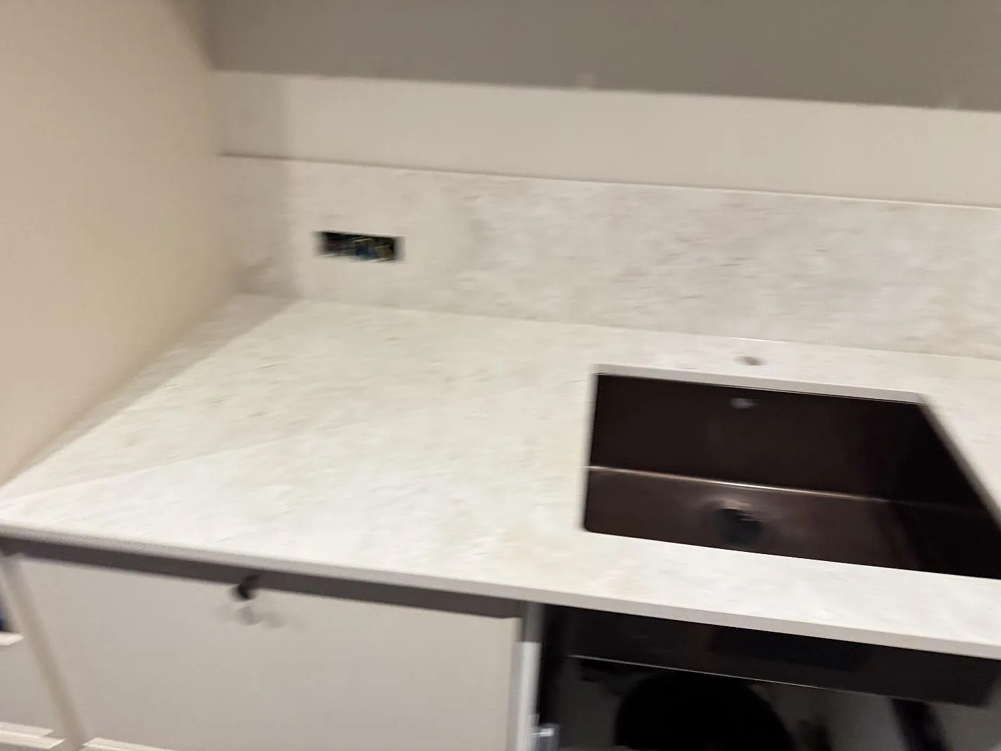 Bred köksvy med matt keramisk bänkskiva i Dekton Tk05 Sabbia, mörk diskho och stänkskydd i Copenhagen.